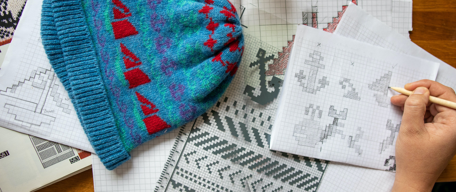 Designing patterns for knitwear , a blue and red knitted hat with green hints rest on a table 